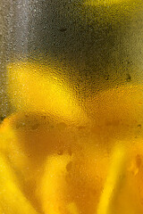 Cold lemonade. Condensation on the glass. Water drops close up. Refreshing vitamin drink. Chilled water with lemon. Citrus fruit. Vitamin C. Orange fruit on a dark background. Fruit splash.