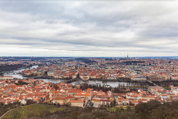Fototapeta na wymiar Aerial panorama view of Prague cityscape with many historic buildings and Vltava river flowing through the old town on a cloudy day from top of Petrin Hill, Czech Republic