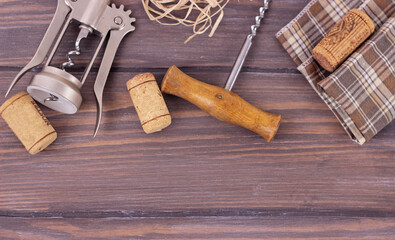 Corkscrew and corks on an old wine barrel texture close up.Wine suplies on dark barn boards with copy space for text.Banner.