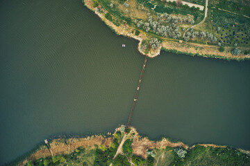 Aerial drone view of an old and broken bridge connecting one river bank to another