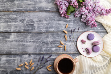 Purple macarons or macaroons cakes with cup of coffee on a gray wooden background. Top view, copy space.