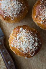 Flat lay of the homemade brioche buns with pearl sugar with a knife on the side on a kitchen's old table.Rustic style food.