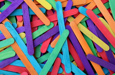Multicolored popsicle sticks in bulk in shades of purple red light blue yellow orange green for desktop background d
