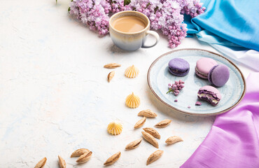 Purple macarons or macaroons cakes with cup of coffee on a white concrete background. Side view, copy space.