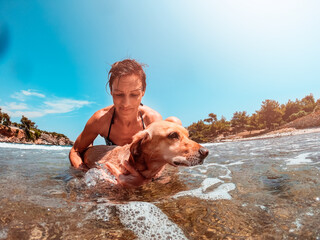 Woman helping her dog to swim in the sea