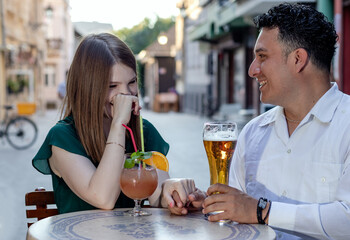Multiracial couple on a first date at street terrace of the cafe. Friendship concept with young multi ethnic people enjoying time together.