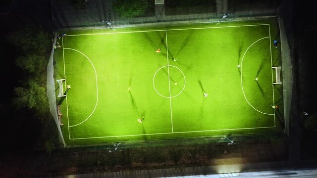 Soccer field, evening/night training of soccer team from above aerial screw rocket drone footage