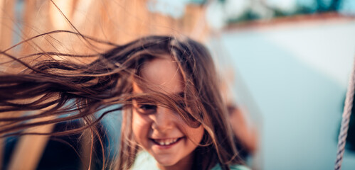 Fototapeta na wymiar Little girl long hair flying in the air while she sitting on swing