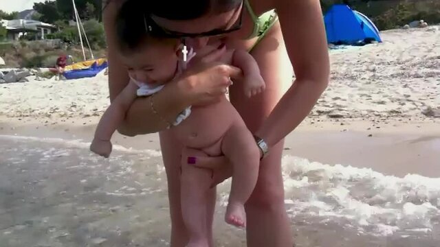 Young baby at the seaside making her first contact with water