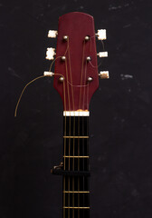 Cap on guitar fretboard on black background. Close plan. Wooden guitar.