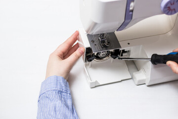 Sewing machine repair. Screwdriver. White sewing machine. Sewing content. Repair of household appliances.