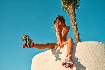 Attractive Caucasian woman in a bikini swimsuit who is rollerblading near the beach in sunny weather.