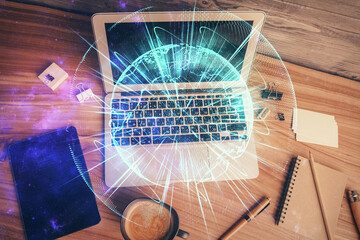 Business theme hologram drawings over computer on the desktop background. Top view. Multi exposure....