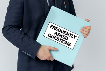 A businessman holds a folder with documents, the text on the folder is - FREQUENTLY ASKED QUESTIONS