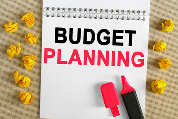 The text is written in the notebook - BUDGET PLANNING. There is a marker on the notebook, next to it is crumpled yellow paper.