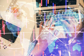 Double exposure of man's hands typing over computer keyboard and business theme hologram drawing. Top view. Financial markets concept.