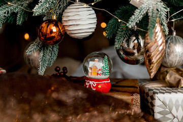 New Year and Christmas gifts decorated with ribbons, candles, snow globe and  Christmas tree with white and gold balls. 