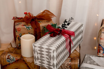 New Year and Christmas gifts decorated with ribbons and berries and candles.