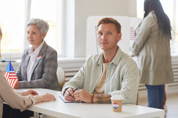 Portrait of modern man looking at camera while working at desk on election day, copy space