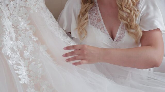 Woman bride stroking her dress with her hands.
