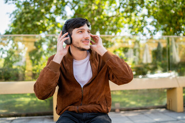 Fototapeta premium Young man listening music with headphones outdoors.