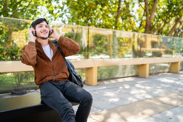 Young man listening music with headphones outdoors.