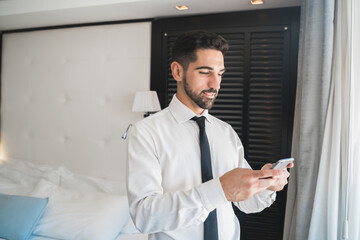 Businessman using his mobile phone at the hotel room.