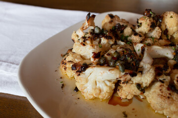 Roasted Cauliflower on White Plate with Napkin and Wood Background