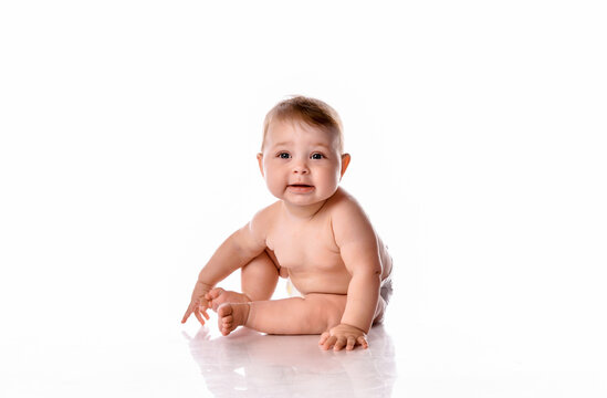One year old naked baby girl sitting on white background.
