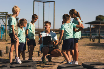 Male fitness coach instructing kids at a boot camp