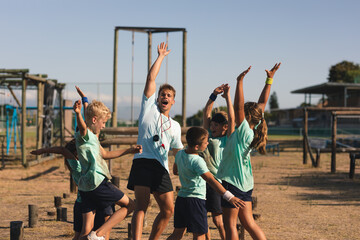 Male fitness coach and kids celebrating with their hands in the air