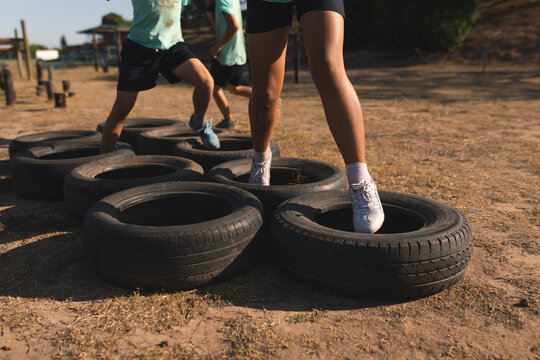 Mid section of kids walking through tires at a boot camp