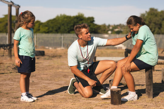 Male fitness supporting injured girl at a boot camp