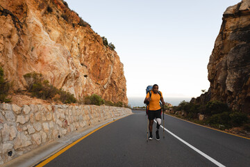 Black African American Man with prosthetic leg hiking on asphalt road