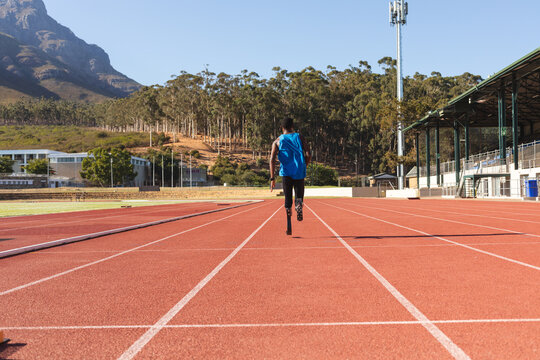 Rear view of Black African American male athlete with prosthetic leg running on race track
