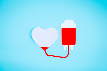 Paper shaping blood bag and heart symbol on table