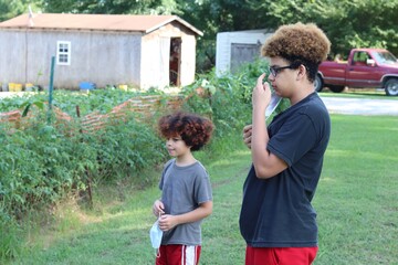 Youngsters watching as farm work is being done with garden and barn in the background