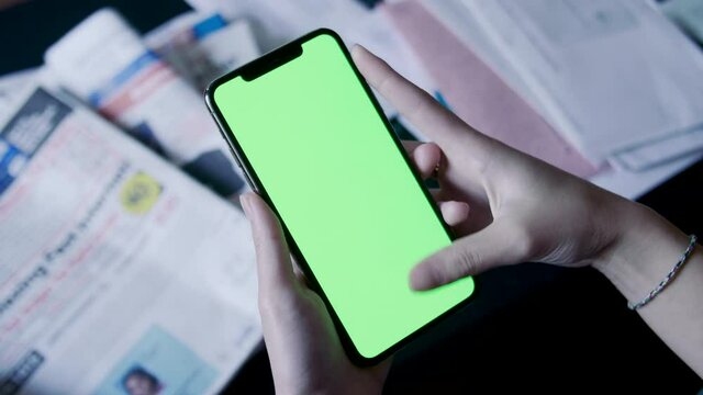 Woman uses phone on top of table that has papers all over
