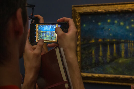 man holding a smartphone, taking a picture in the museum