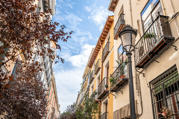 Beautiful street lantern and scenery in the Las Letras neighborhood in central Madrid, with typical Spanish architecture. - obrazy, fototapety, plakaty