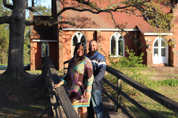 Obraz na płótnie Canvas African American couple standing on a bridge by a church on a sunny day