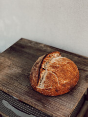 High hydration bread, long and slow cold fermentation, made from wheat flour sourdough just out of the oven on wooden table, banneton and black background