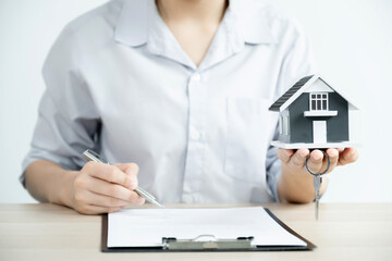home model in Hand a real estate agent and agent explain the business contract, rent, buy, mortgage, loan, or home insurance to the buyer woman