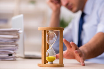 Young male employee in time management concept