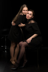 Mom and daughter in the studio on a black background.