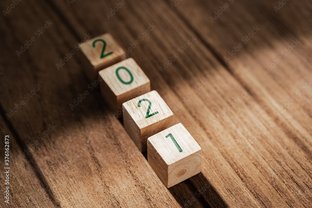 Poster 2021 happy new year on wood block on wood table and concrete wall with sunlight from window.hope new