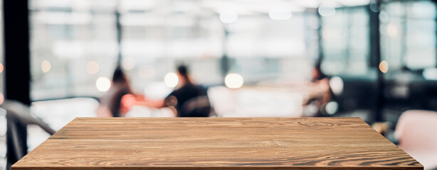 Empty wood table with blur people in coffee shop background bokeh light and leaf foreground,Mockup for display or montage of product,Banner for advertise on online media,business presentation