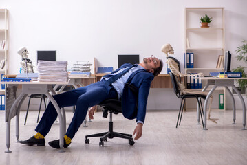 Young male employee with skeletons in the office