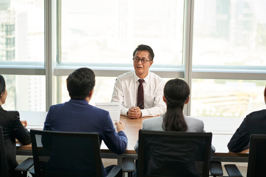 older asian man being interviewed by a group of young hr executives