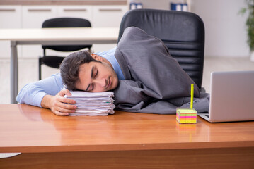 Fototapeta premium Young male employee sleeping in the office